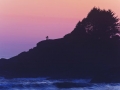 A silhouetted couple explore a rocky headland at dusk near Cox Bay